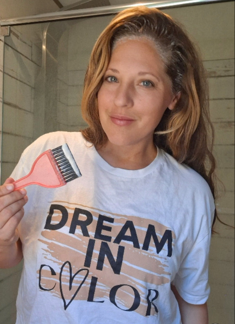 Woman holding a hairbrush with 'Dream in Color' t-shirt in a bathroom